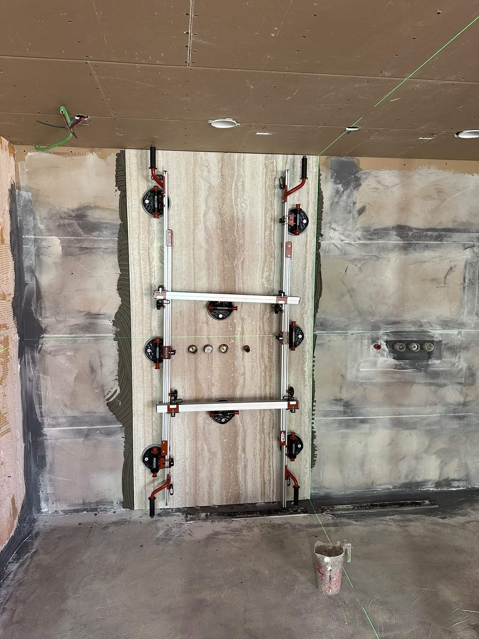 Grote travertinlook slab wordt met zuignappen en laser op de wand gezet