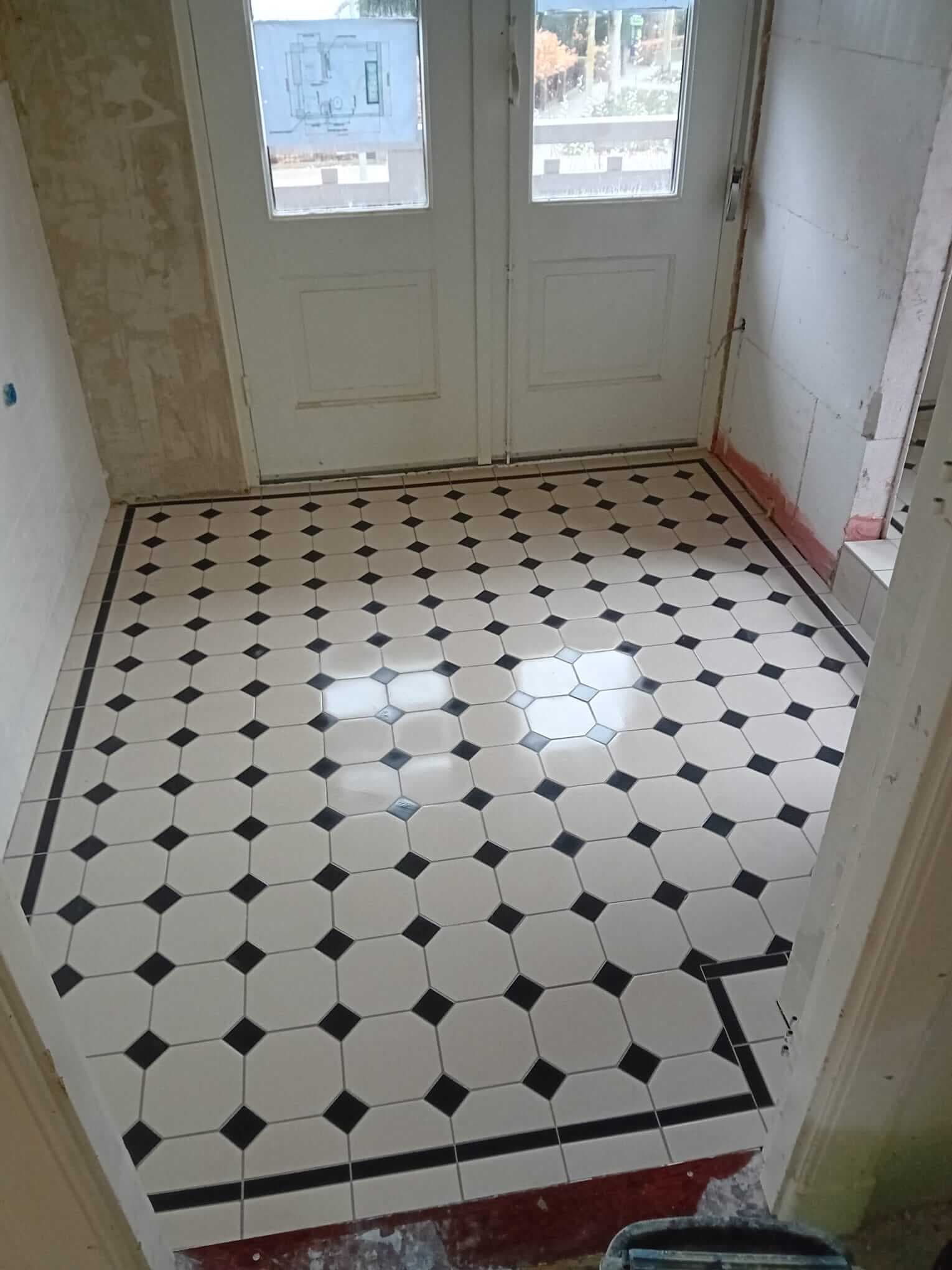 Klassieke zwart-witte octagonvloer met sierrand in een entree