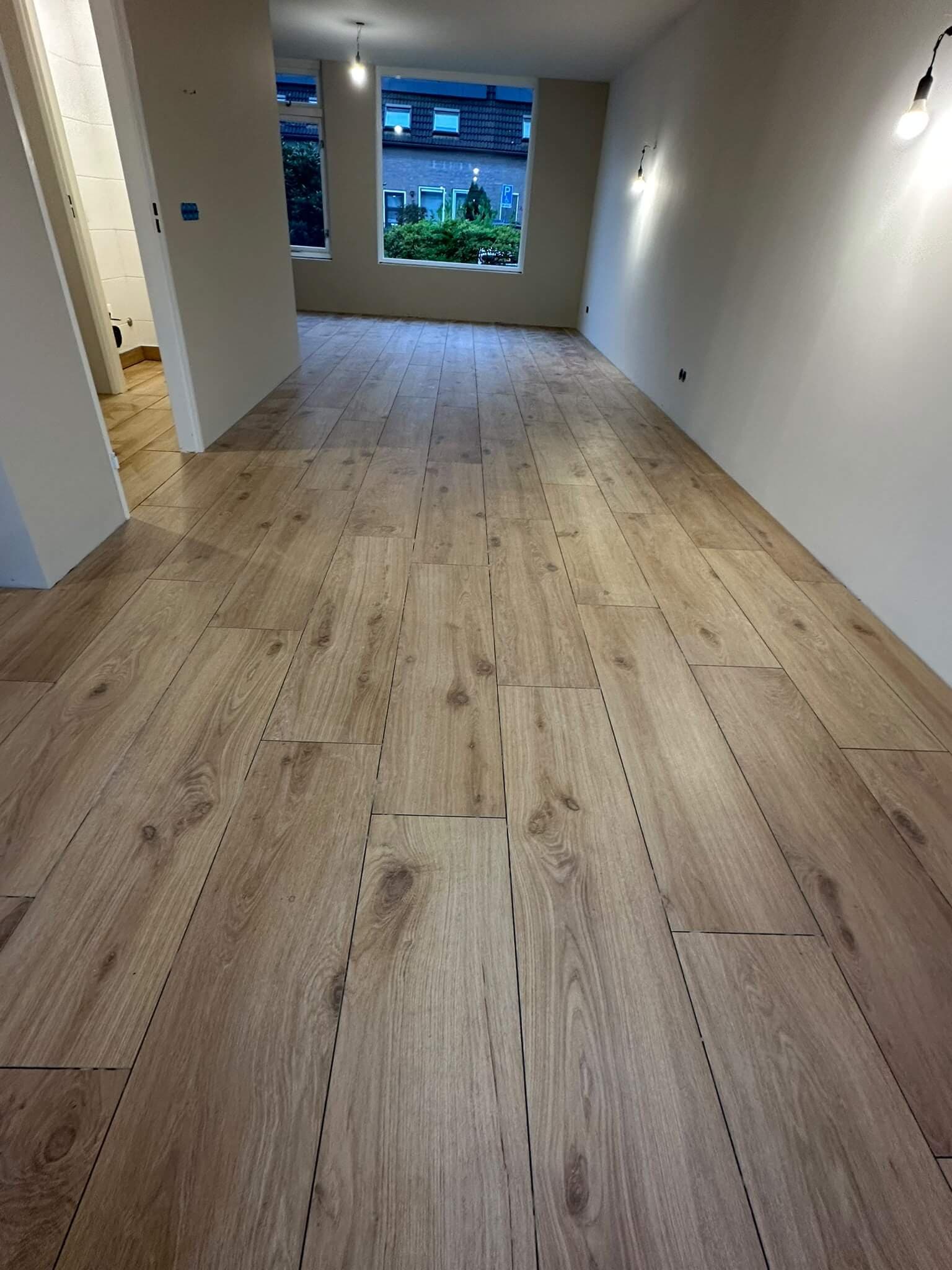 Houtlook vloertegels in lange planken in een lege woonruimte